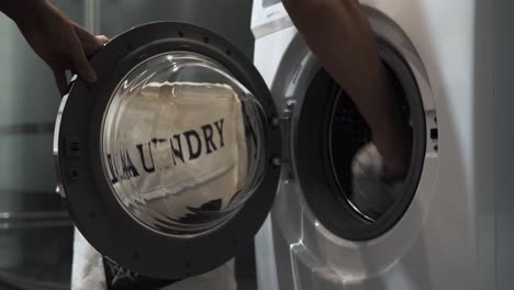 4k stationary shot of a man doing laundry and taking white linen out of a washing machine