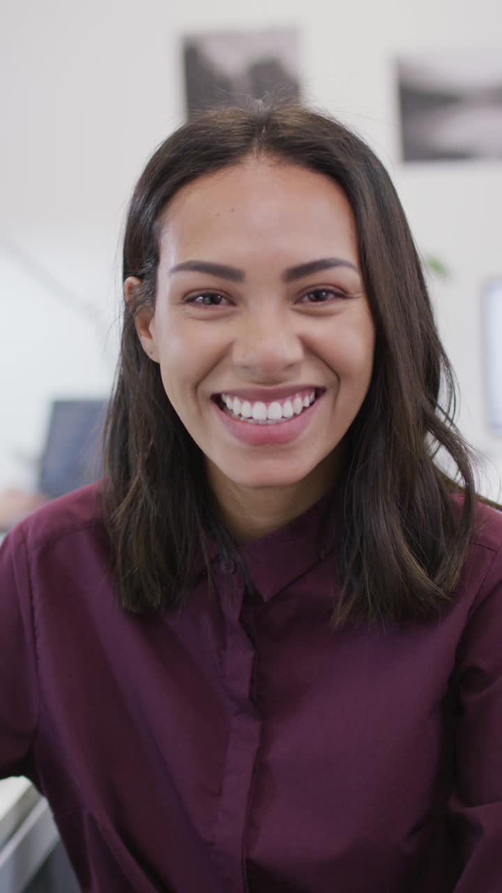 retrato de video vertical de una mujer biracial sonriente en el trabajo