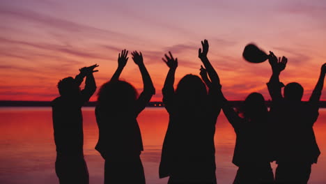 friends dancing at sunset by the lake