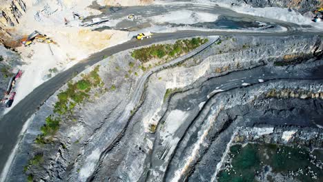 quarrying heavy machines working in upper level of a deep quarry summer morning
