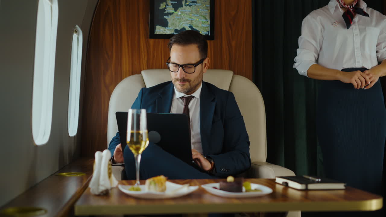 Businessman working on a private jet with champagne and snacks