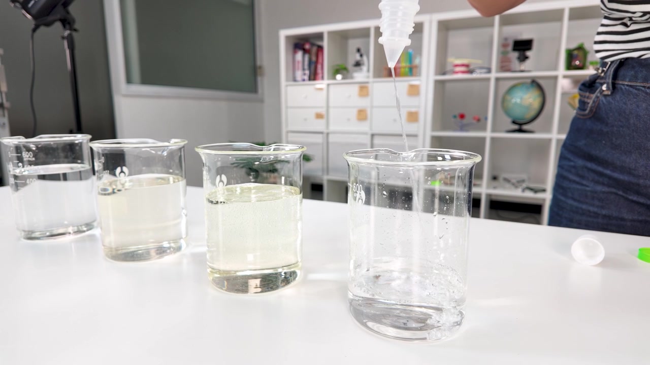 Liquido chimico trasparente versato in un becher di vetro durante un esperimento didattico in classe