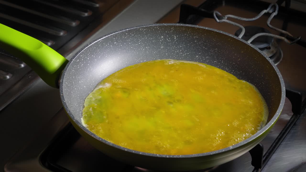Lo chef versa le uova sbattute nella padella, preparando uova strapazzate per pranzo.