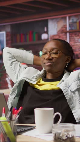 vertical video joyous woman relaxing at home, sitting back and watching tv show on laptop