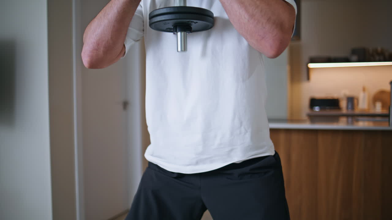 Athletic man squatting dumbbell at home strength training closeup. Sport workout
