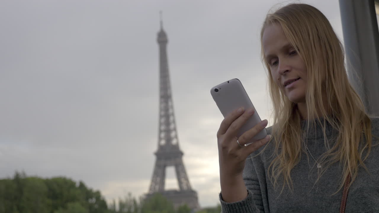 mujer usando un móvil y tomando una foto de la torre eiffel