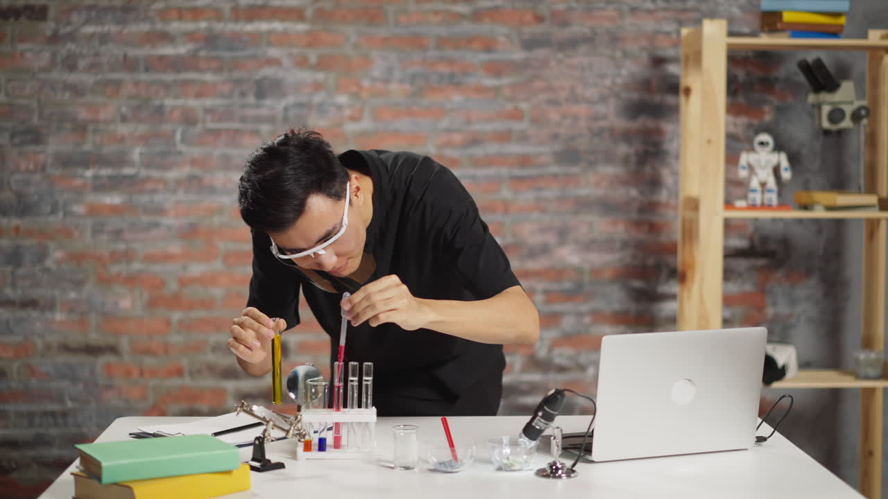 el estudiante asiático agrega líquido al material de prueba en la mesa