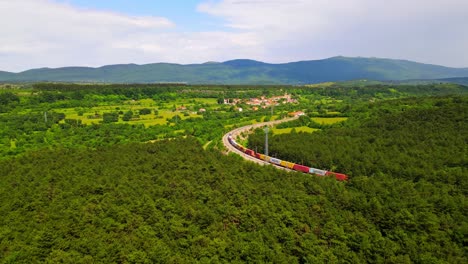 stunning aerial 4k drone footage of a cargo train that glides through a lush, forested landscape