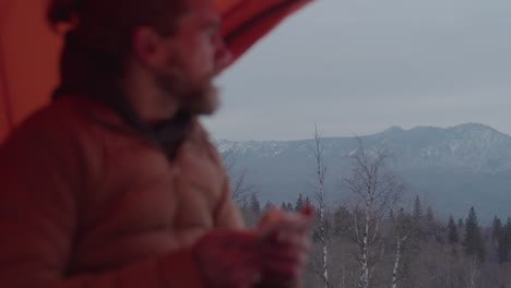 man using smartphone in camping tent on mountain top
