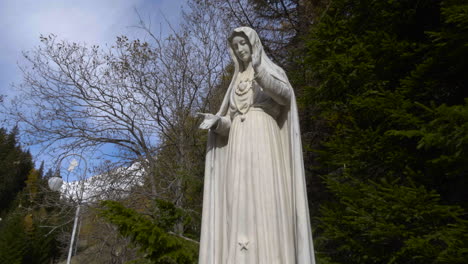 a white big statue of mother mary outside in the town