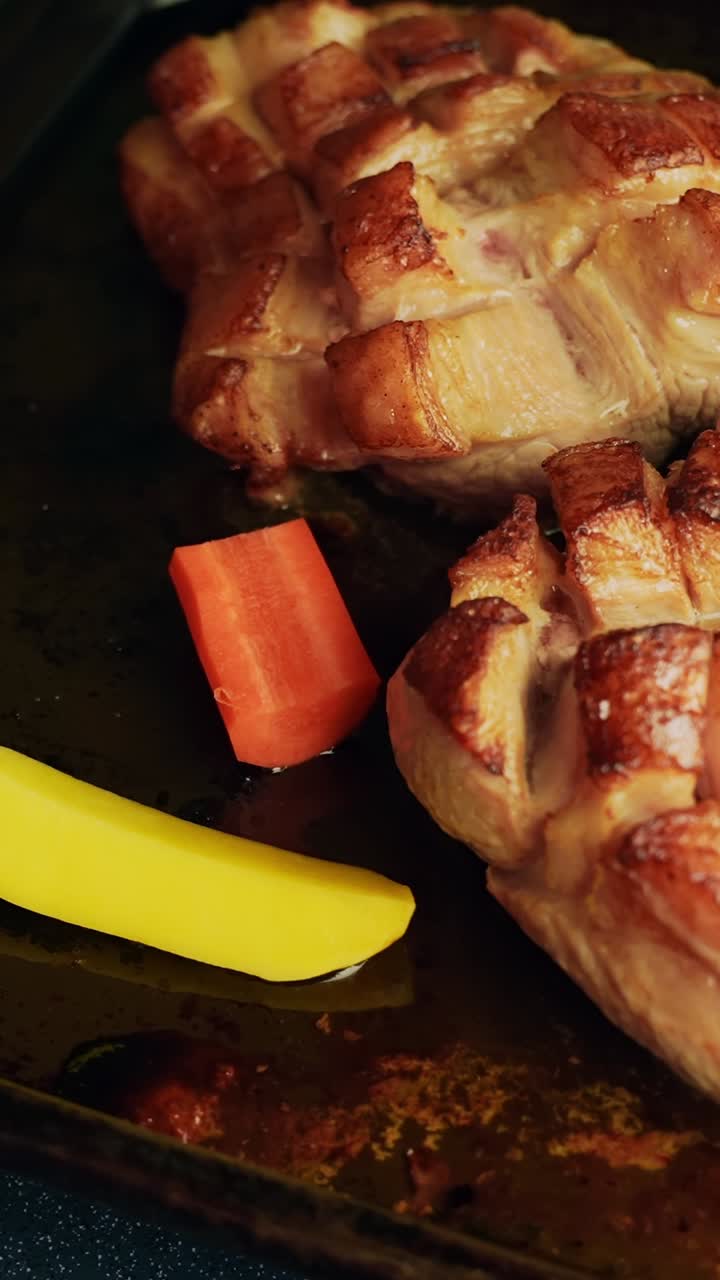 Primo piano verticale dell'aggiunta di patate, carote e pezzi di patate dolci in una teglia con pancetta di maiale parzialmente cotta, mescolando le verdure nei succhi caldi della padella prima di finire in forno.