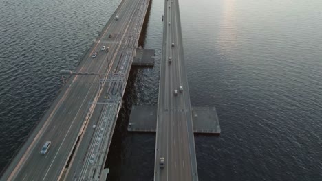 captivating drone flight during the golden hour showcases a beautiful sunset over seattle’s stunning floating bridge. the traffic of cars adds a cinematic touch to the scene.