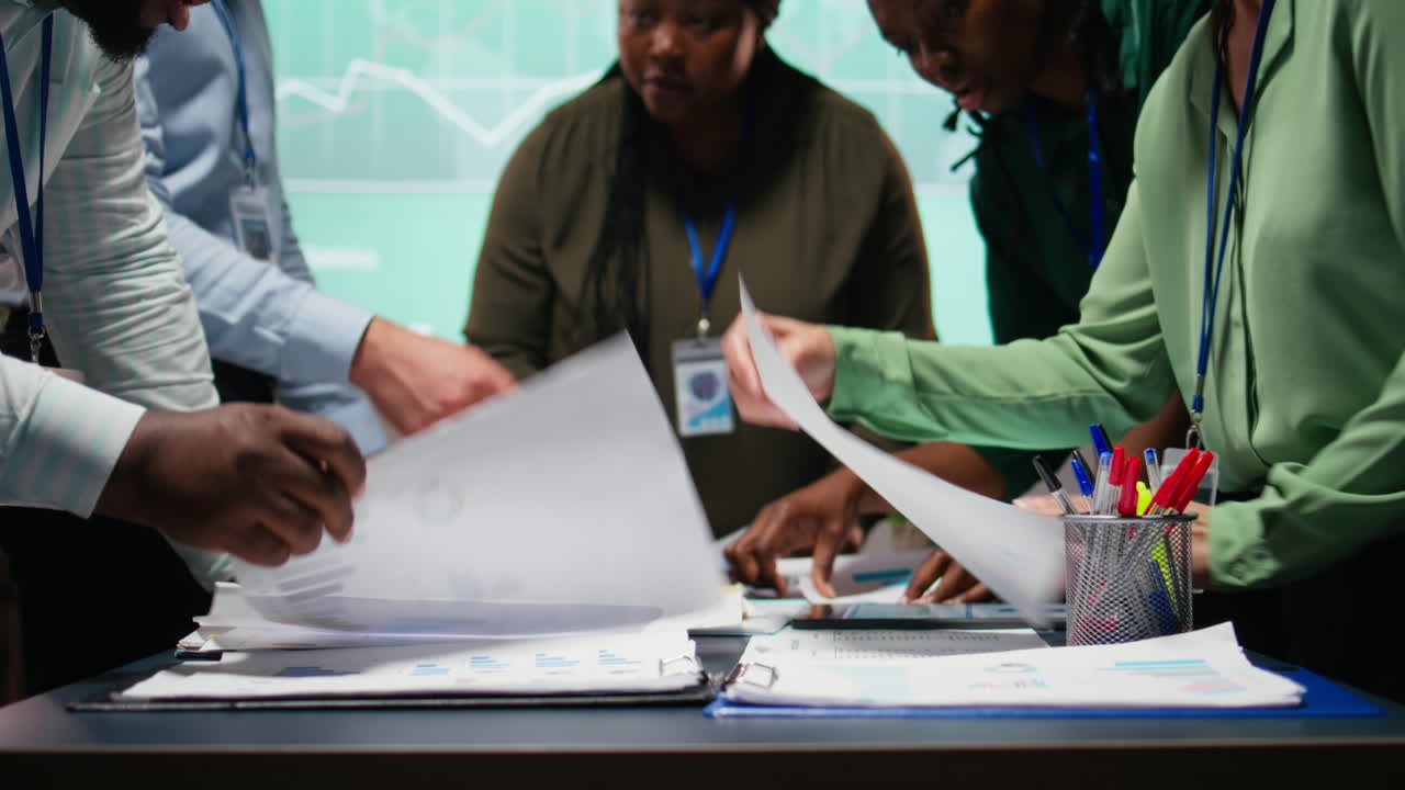 Multiethnic forecasting team reviewing report files during important meeting