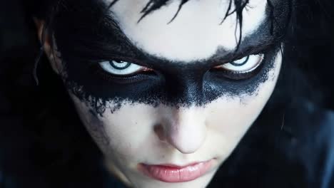 a close up of a person with black makeup and blue eyes