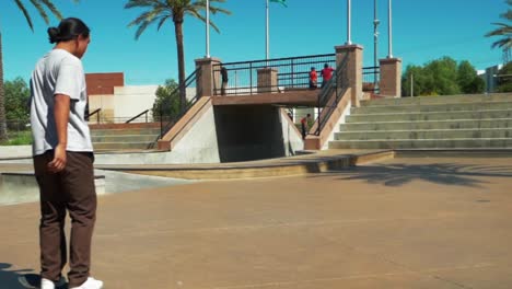 patinador masculino adolescente en un parque de patinaje en un día soleado de verano montando en patineta, cámara lenta