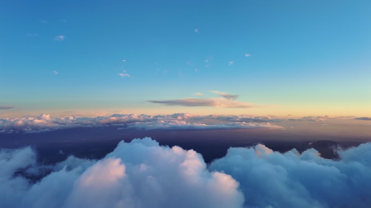 En pilots perspektiv mens den flyver fredeligt over gyldne cumulusskyer over havet ved solnedgang, med toppen af skyerne oplyst af blødt og varmt orange lys. Optagelse fra cockpit.