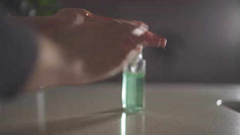 woman's hand enters frame and applies hand sanitizer