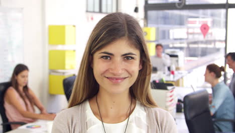 Woman-in-office-walks-into-focal-plane-and-smiles-to-camera