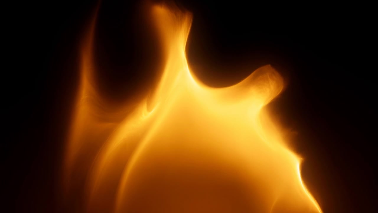 Close view follows luminous orange flame forms as they stretch upward, fold and narrow over time, with soft amber gradients, deep black surroundings and smooth changing contours.