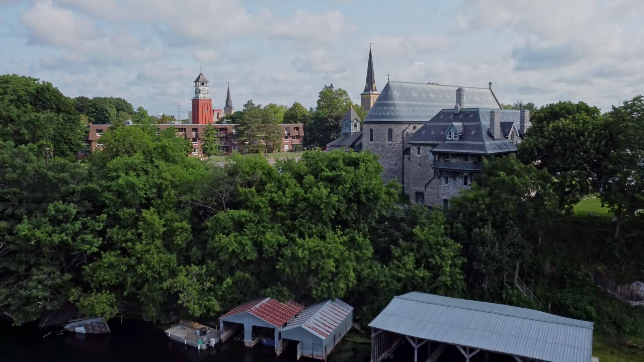 Church on a hill drone tracks down to river with boats passing by
