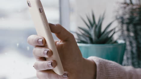 close up woman hand using smartphone browsing online messages reading social media enjoying mobile communication standing by window relaxing at home on cold rainy day