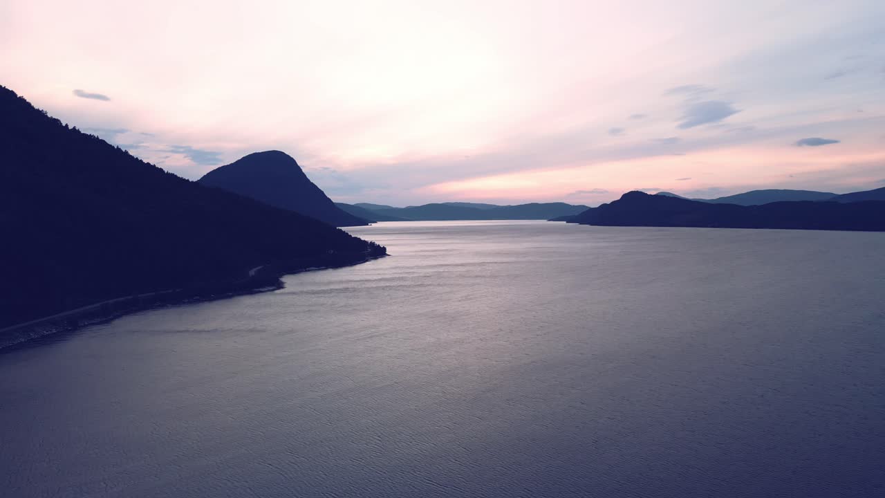 노르웨이의 조용한 바다 위로 공중을 날며 일출의 태양에 물든 하늘