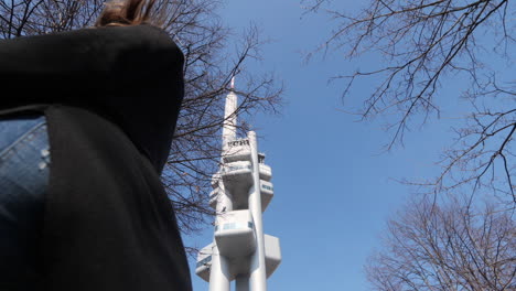 chica con mascarilla caminando al aire libre por una torre moderna durante la pandemia del virus covid-19, cámara lenta de ángulo bajo