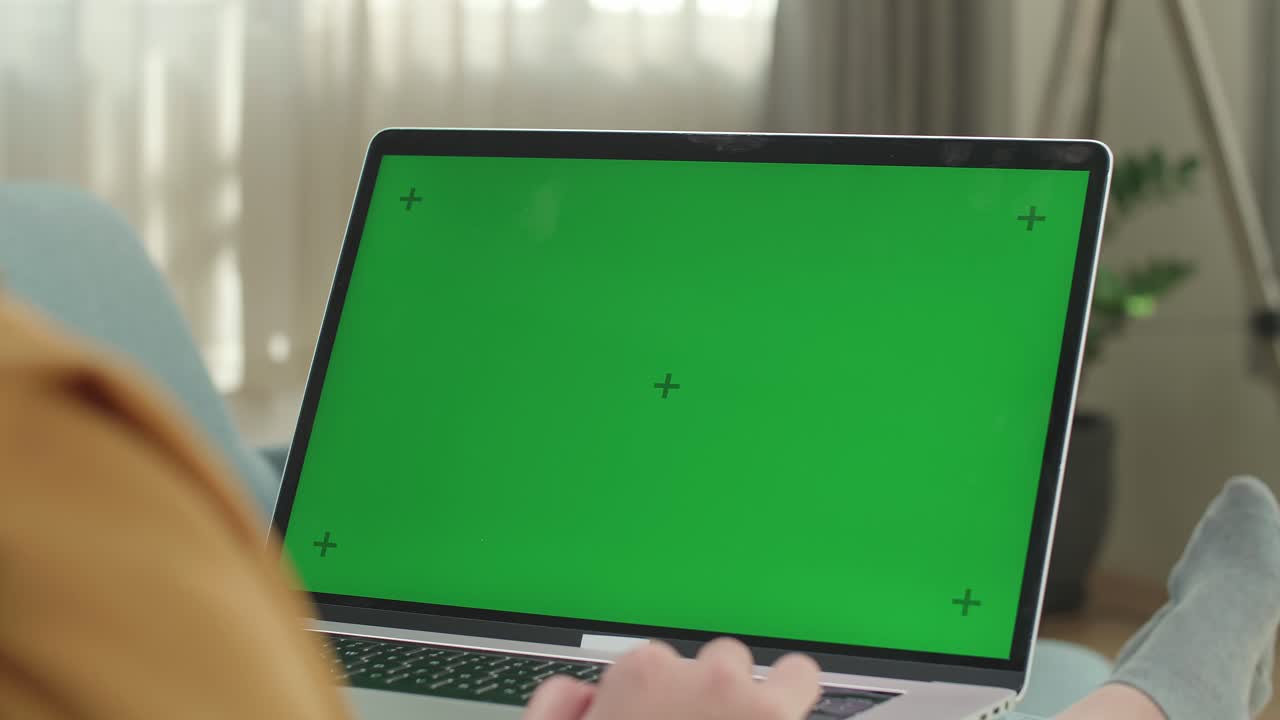 Asian Woman Sitting On Couch And Using Laptop Computer With Mock Up Green Screen Display