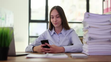 young woman using her smartphone at an office desk