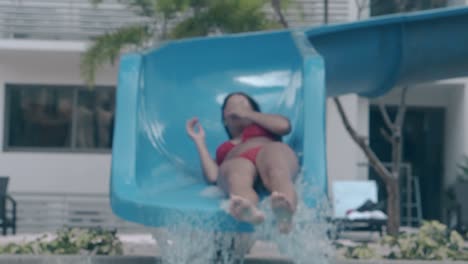 una chica en bikini viaja en tobogán acuático junto a la piscina en cámara lenta.