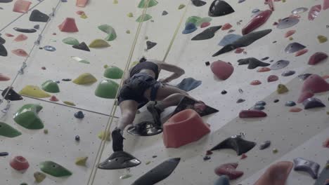 persona que sube a una pared de roca interior colorida, desafío deportivo y de fitness