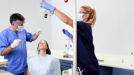 dentist talking with patient while nurse prepares the tools