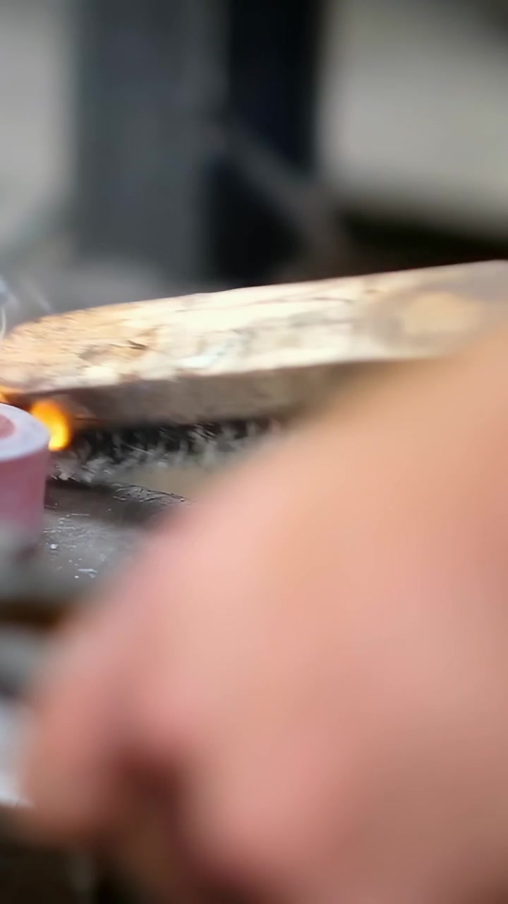 Vertical video: Brushing worker hands contacting red disk with wire brush, removing metal dust