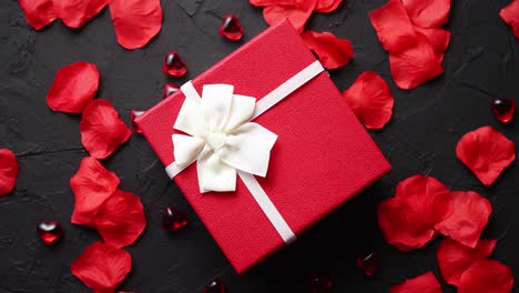 gift box on black stone table  romantic holiday background with rose petals