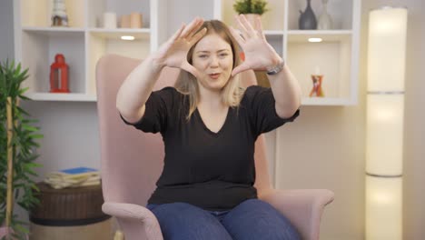 young woman making heart symbol for camera.