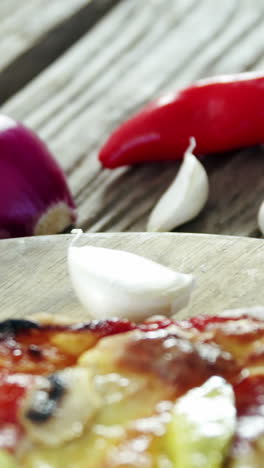 italian pizza on wooden table with vegetables and spices