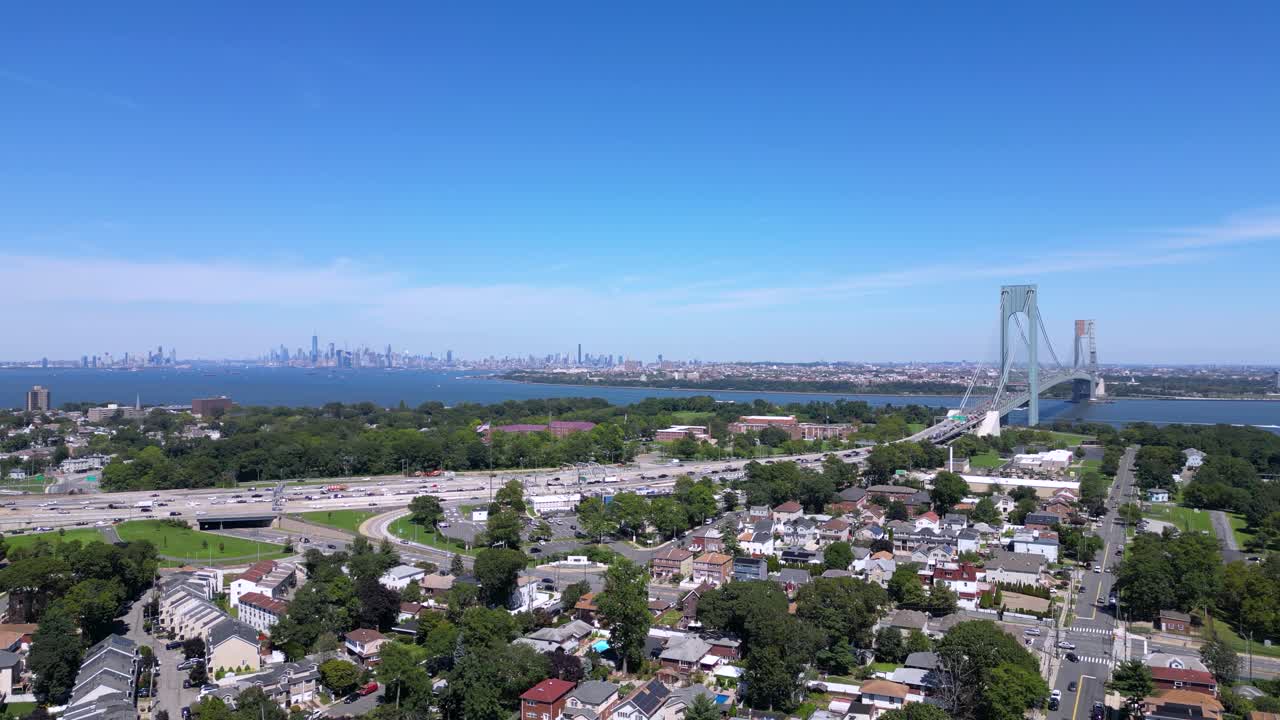Stunning aerial view of Staten Island and the Verrazzano-Narrows Bridge with a clear skyline, waterfront, and residential neighborhoods under a bright blue sky