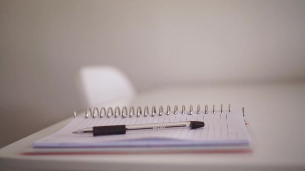 hand picking up pen from spiral notebook on desk. Business, writing, and office concept footage, ready to take notes or sign document.