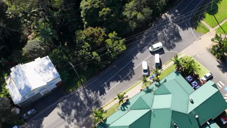 drone footage captures a sunny day over uki, nsw, showcasing roads, vehicles, and green-roofed buildings