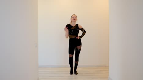 young and attractive female dance performer dancing alone inside a home wearing a dark outfit in slow motion