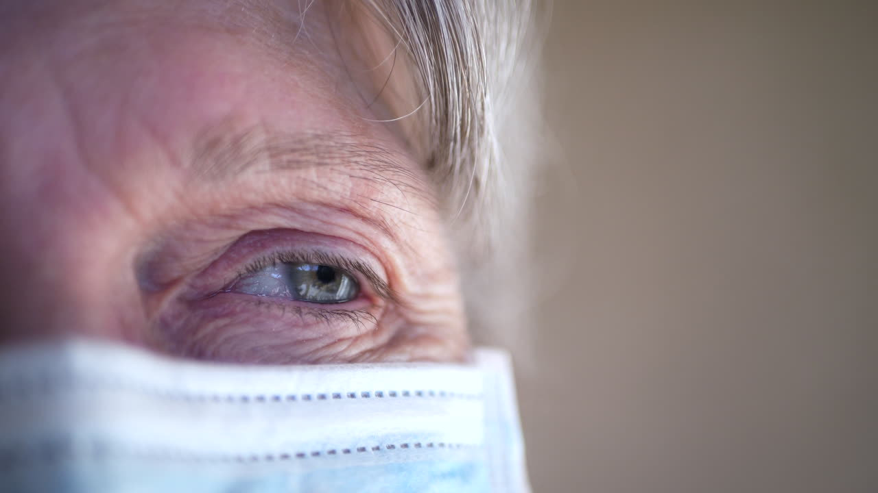 Primo piano del volto di una donna anziana che indossa una mascherina medica in ospedale per prevenire malattie contagiose e infezioni