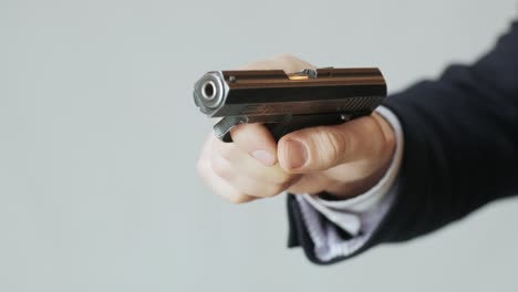un hombre de negocios en una chaqueta con un arma en la mano recarga el perno y está listo para disparar