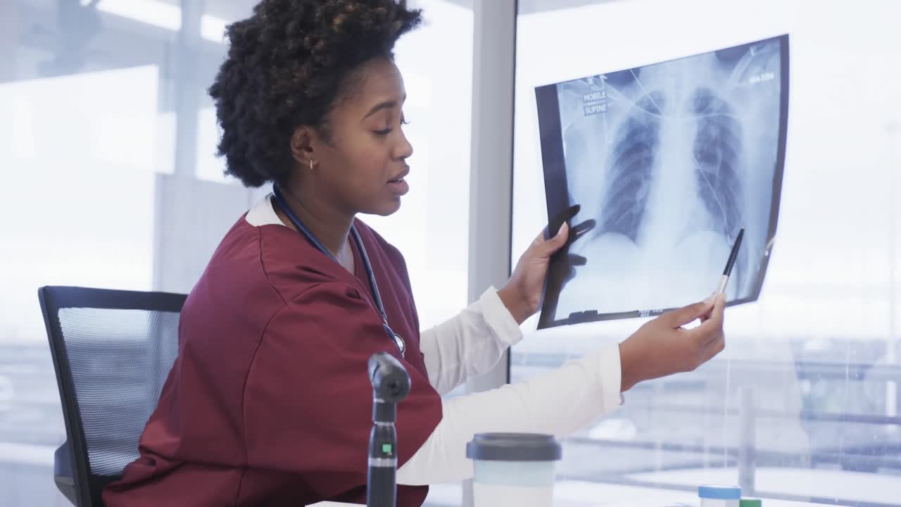 médica afroamericana que sostiene una imagen de rayos x haciendo una videollamada en la oficina del hospital, cámara lenta