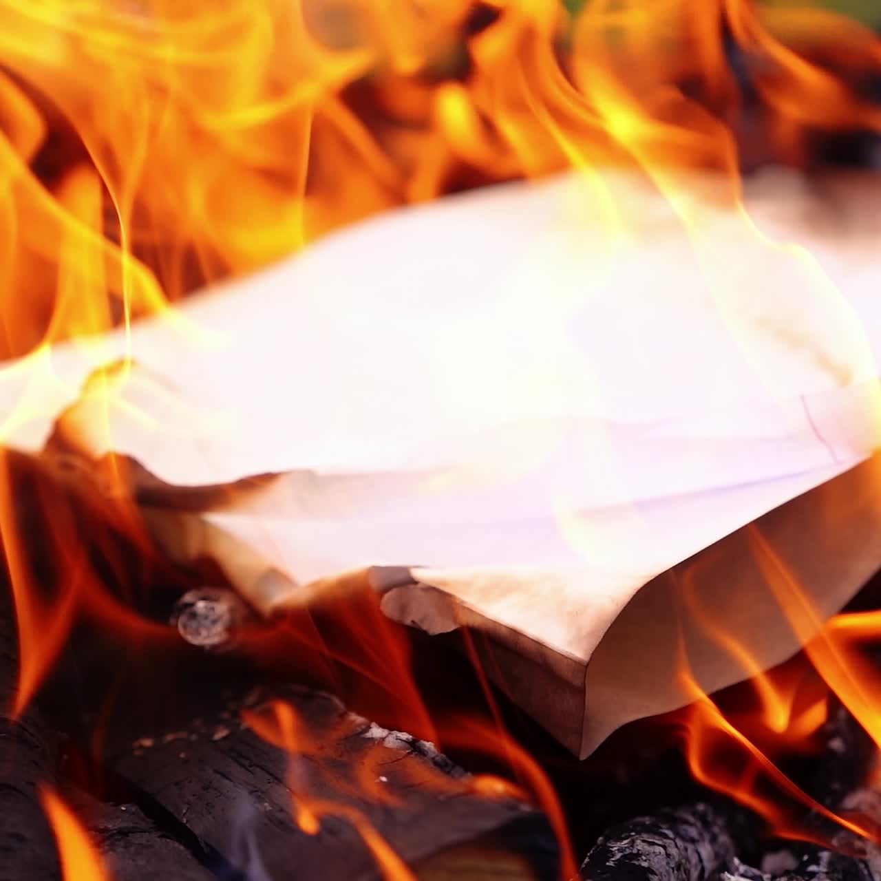 Bright flame over charcoals. White paper falling into the fire and burning out. Wooden logs burning for barbecue. Slow motion.