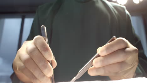 Midsection-of-male-surgeon-in-gloves-using-scalpels-during-operation,-slow-motion