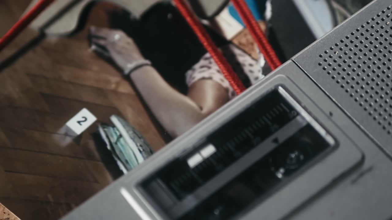 una junta de investigación de un detective revelando fotos de la escena del crimen y una grabadora reproduciendo declaraciones de testigos