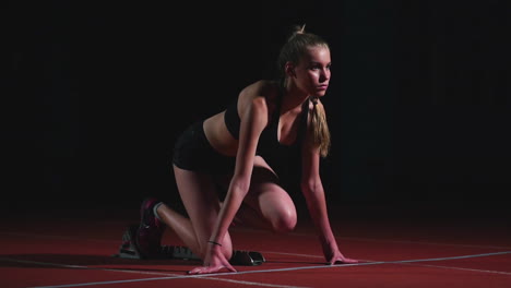 Female-athlete-on-a-dark-background-to-run-the-sprint-of-the-cross-country-pad-on-the-treadmill-on-a-dark-background