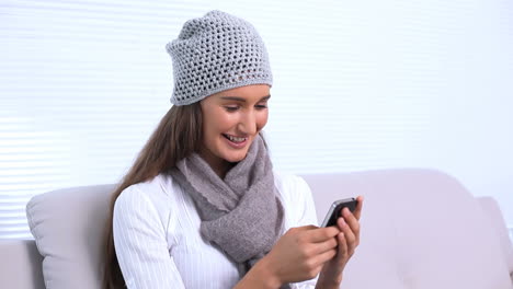 Brunette-sitting-on-sofa-texting-a-message-with-her-phone