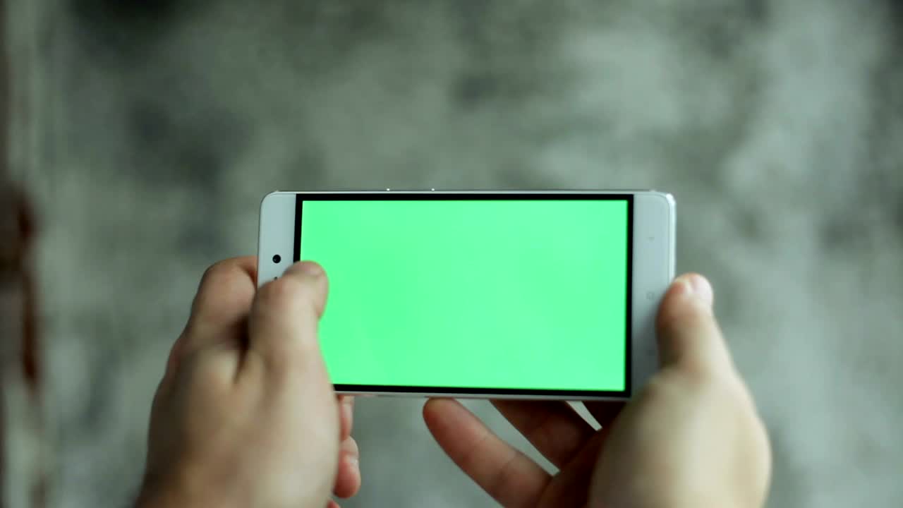클로즈업 남자 손을 들고 녹색 화면 수직으로 전화를 만지고 있습니다.