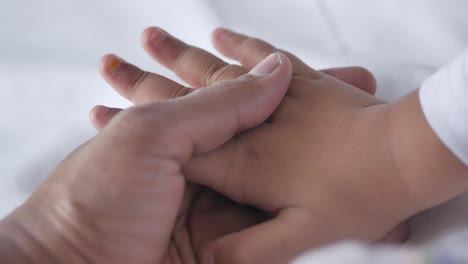 father holding hand of baby child, close up